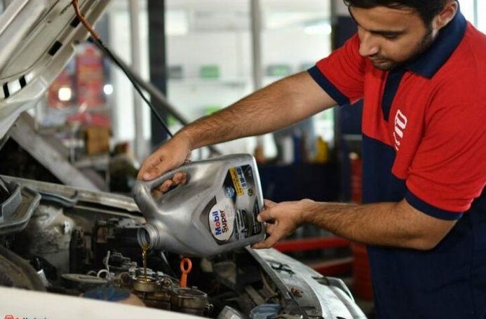 Technician checking the oil level under the hood