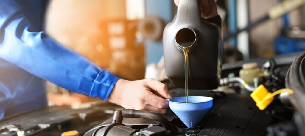 Technician pouring motor oil through a funnel